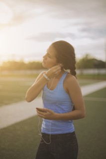 Mixed race athlete listening to mp3 player on sports field