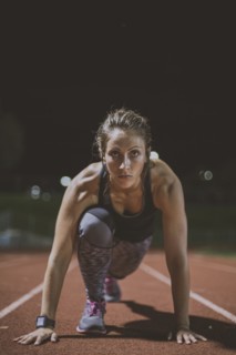 Caucasian runner in starting position on sports field