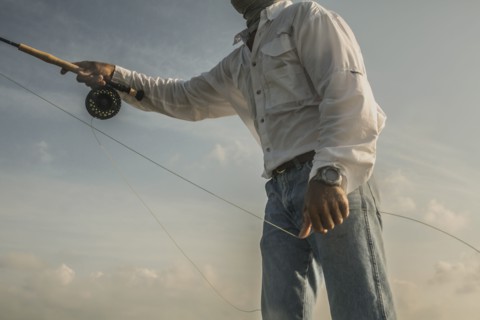Close up of Caucasian man fishing under blue sky