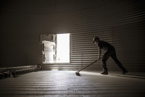 Caucasian boy sweeping empty silo