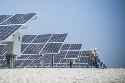 Caucasian technicians talking near solar panels