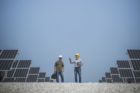 Caucasian technicians talking near solar panels