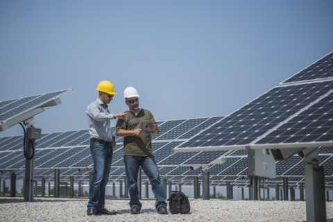 Caucasian technicians talking near solar panels