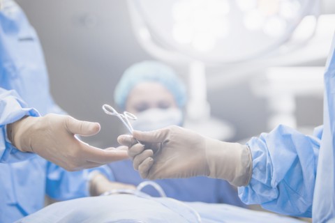 Surgeons handing forceps in operating room