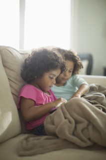 Sisters using digital tablet on sofa