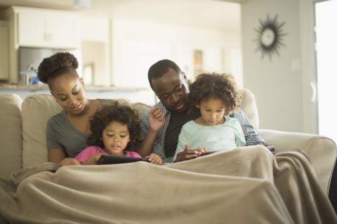Family using digital tablets on sofa