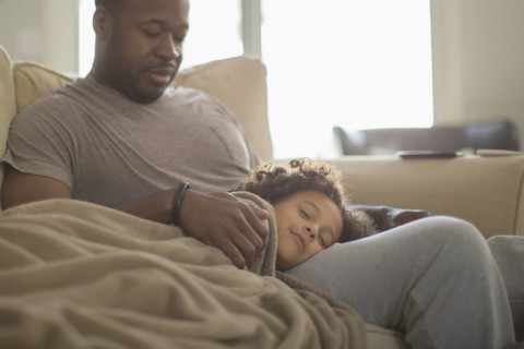Father and daughter snuggling on sofa
