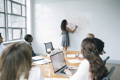 Businesswoman writing on whiteboard in meeting