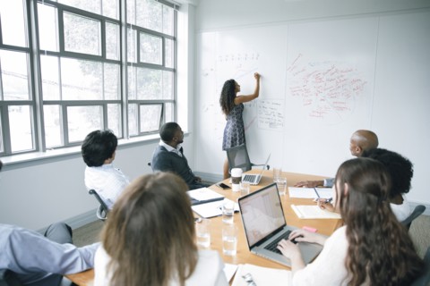 Businesswoman writing on whiteboard in meeting