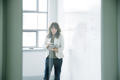 Caucasian businesswoman holding digital tablet near whiteboard