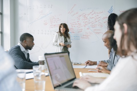 Businesswoman holding digital tablet near whiteboard in meeting