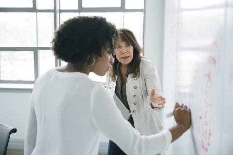 Businesswoman writing on whiteboard in meeting