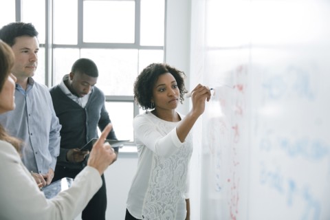Businesswoman writing on whiteboard in meeting