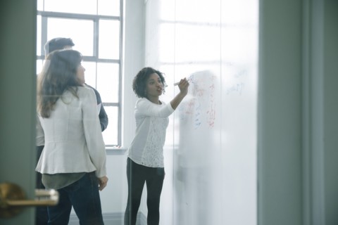 Businesswoman writing on whiteboard in meeting