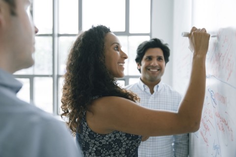 Businesswoman writing on whiteboard in meeting