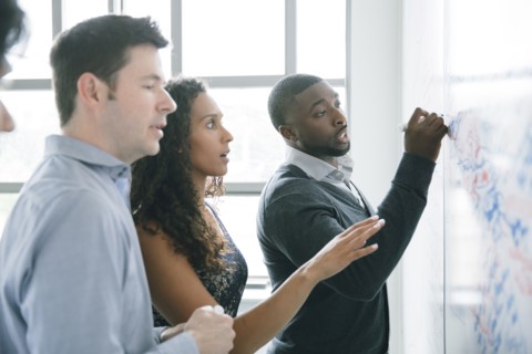 Businessman writing on whiteboard in meeting