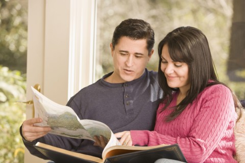 Hispanic couple looking at atlas