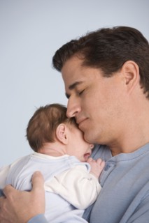 Hispanic father hugging baby