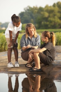 Teacher and students sitting on rock near river