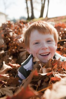 Caucasian boy playing in autumn leaves