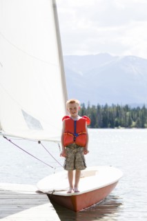 Boy in life jacket standing on sailboat