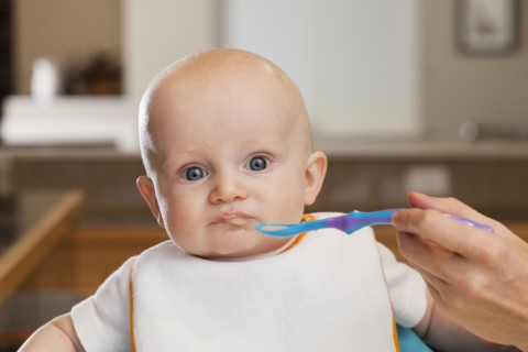 Caucasian mother feeding baby in high chair