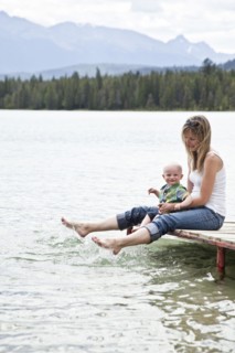 Caucasian mother and baby sitting by lake