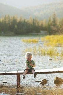 Caucasian boy sitting on wooden deck over lake