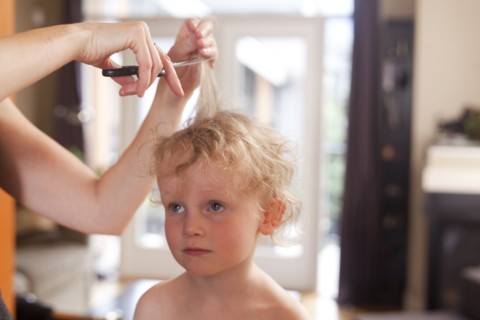 Caucasian mother cutting hair of son