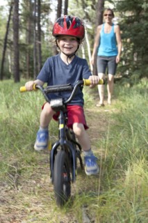 Caucasian mother watching smiling son on bicycle