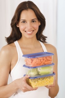 Hispanic woman holding vegetables in plastic storage containers