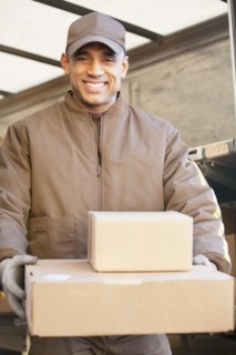 Smiling Hispanic delivery man carrying cardboard boxes