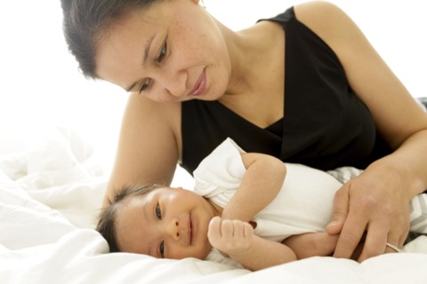 Mother laying on bed with baby son