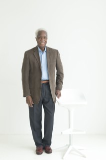Portrait of older Black man leaning on store