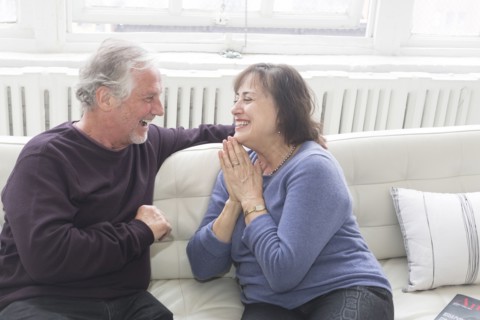 Older couple sitting on sofa and laughing