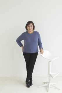 Confident older Mixed Race woman leaning on stool