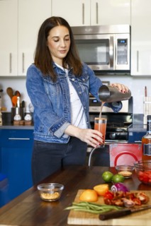 Woman pouring cocktail in kitchen