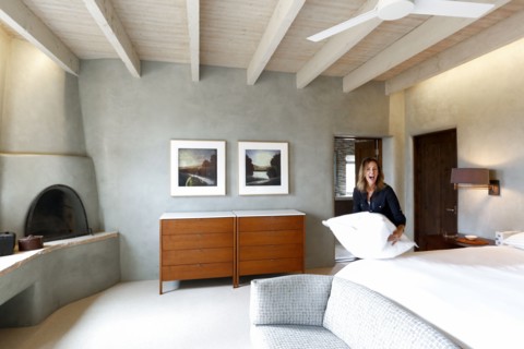 Laughing Caucasian woman holding pillow in bedroom
