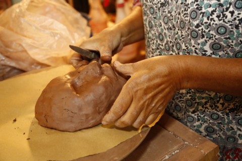Mixed race woman shaping clay mask in art studio