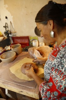 Mixed race woman shaping clay mask in art studio