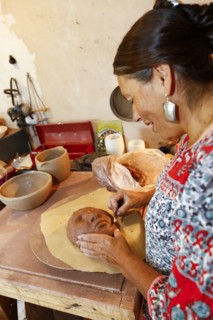 Mixed race woman shaping clay mask in art studio