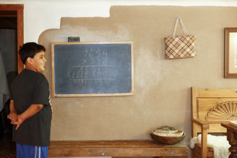 Proud Native American boy standing near equation on blackboard