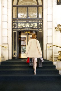 Glamorous Caucasian woman carrying shopping bags to luxury building