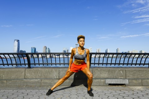 Mixed race woman stretching legs at waterfront