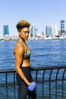 Mixed race woman lifting dumbbells at waterfront