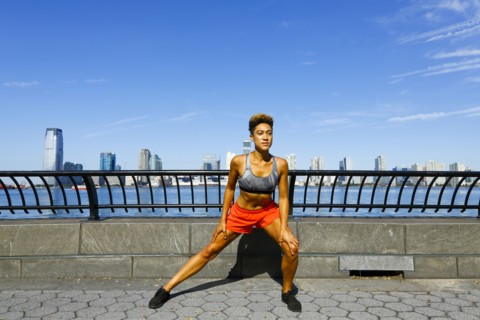 Mixed race woman stretching legs at waterfront