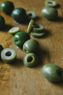 Sliced green olives on cutting board