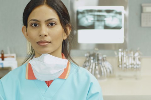 Indian female dental assistant next to x-rays