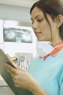 Indian female dental assistant writing on chart