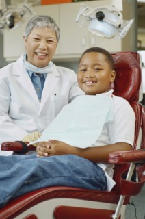 Senior Asian female dentist and African boy in dentist's chair